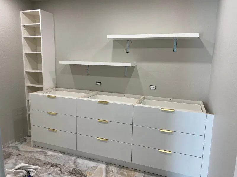 Built-in dresser with gold pulls, floating shelves and a tall bookcase