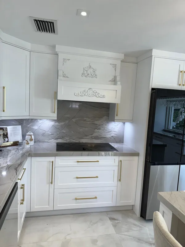 Custom range hood with carved appliques over white drawer bases