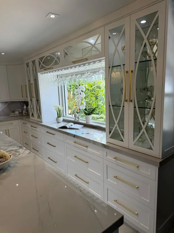 Wall of white cabinetry with arched mirrored glass doors and brushed-gold pulls