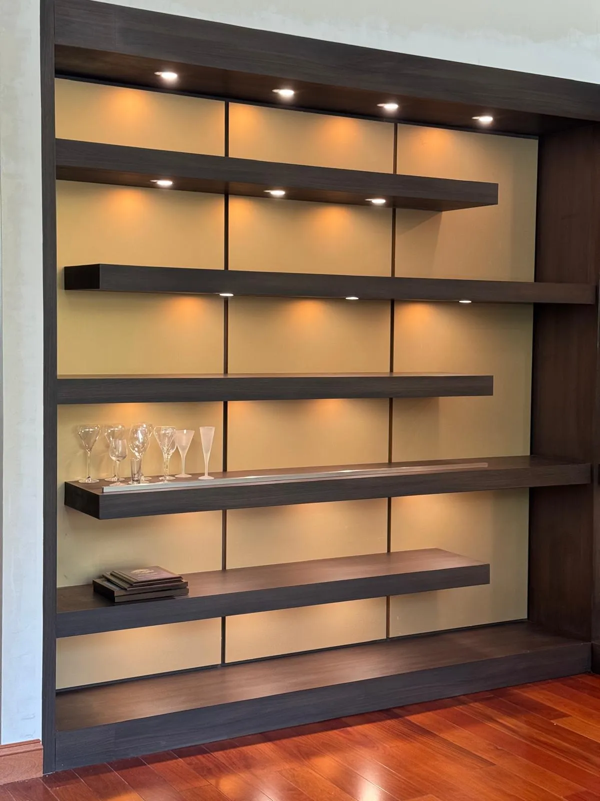 Backlit wall unit with walnut floating shelves and warm panel lighting