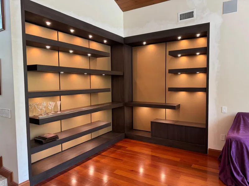 Corner display wall with lit floating shelves in dark walnut